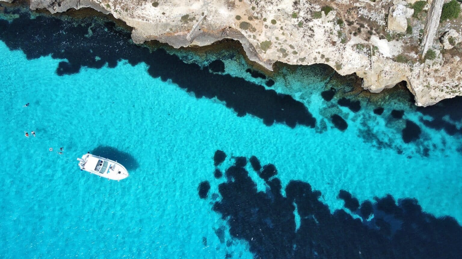Travel facilitator guiding a small group tour in Sicily, with clients enjoying a boat trip and swimming in the beautiful sea.